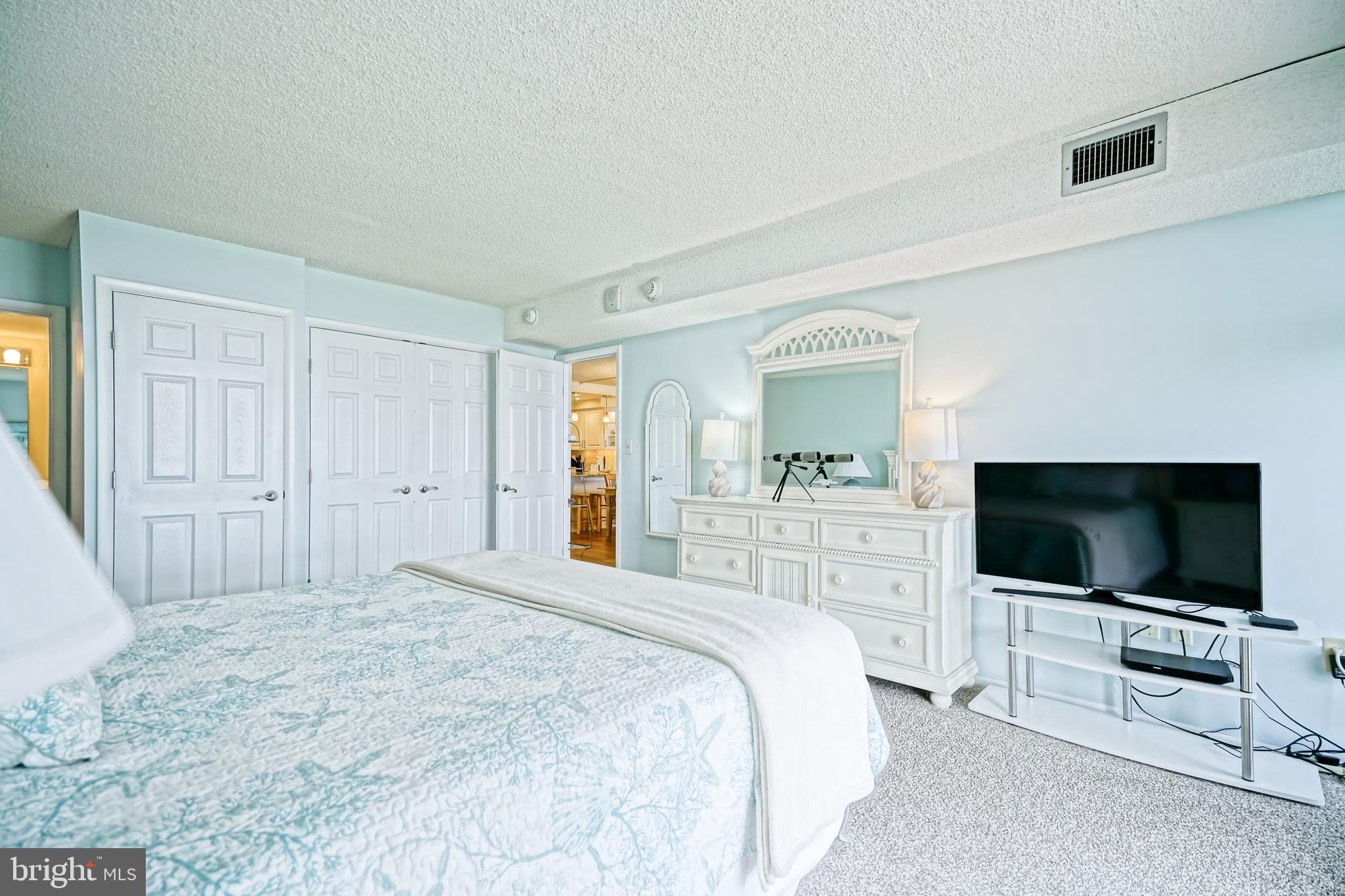 604 Dover House Road, Unit 604S Bethany Beach, DE 19930 - Photo 28 of 43 a bedroom with a flat screen tv on dresser and a refrigerator