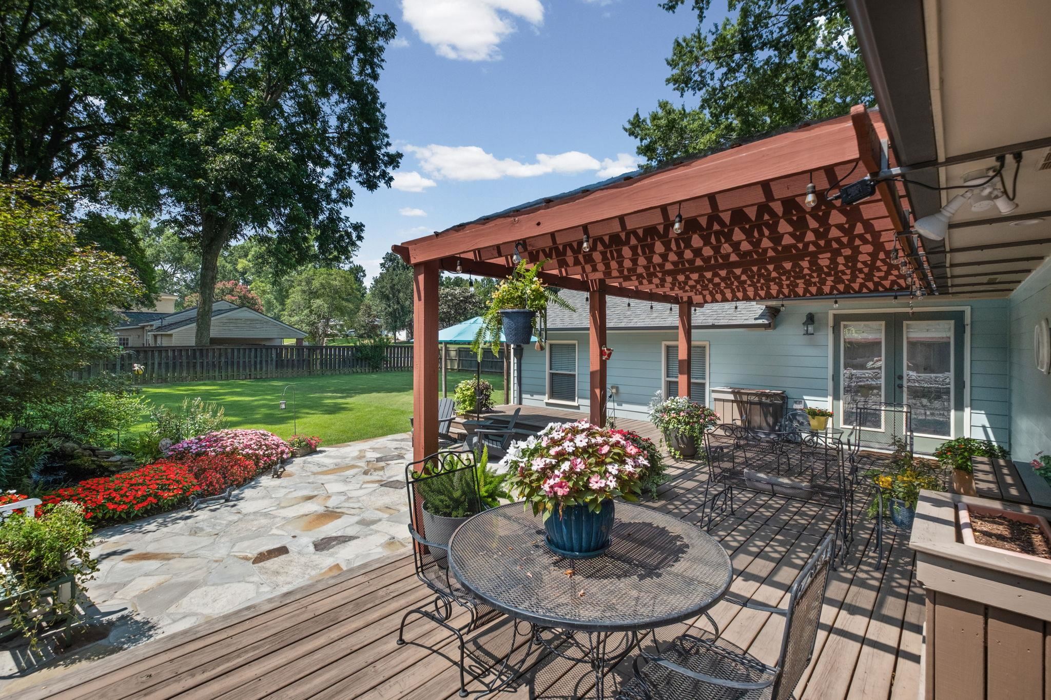5079 Walnut Grove Road Memphis, TN 38117 - Photo 30 of 40 Expansive outdoor deck with a red-stained pergola, flagstone patio, and mature landscaping
