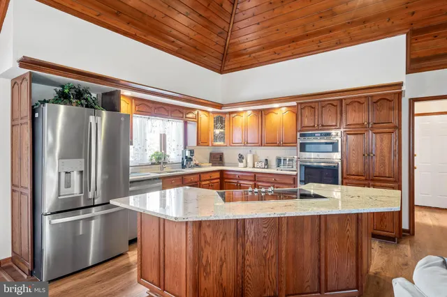 a kitchen with stainless steel appliances granite countertop a refrigerator a sink and a stove