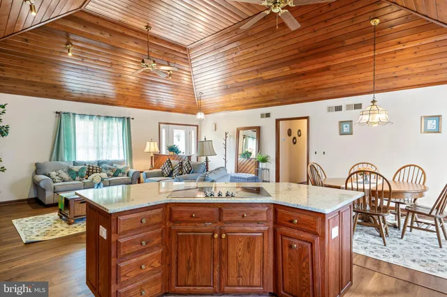 a living room with granite countertop furniture a dining table wooden floor and kitchen view