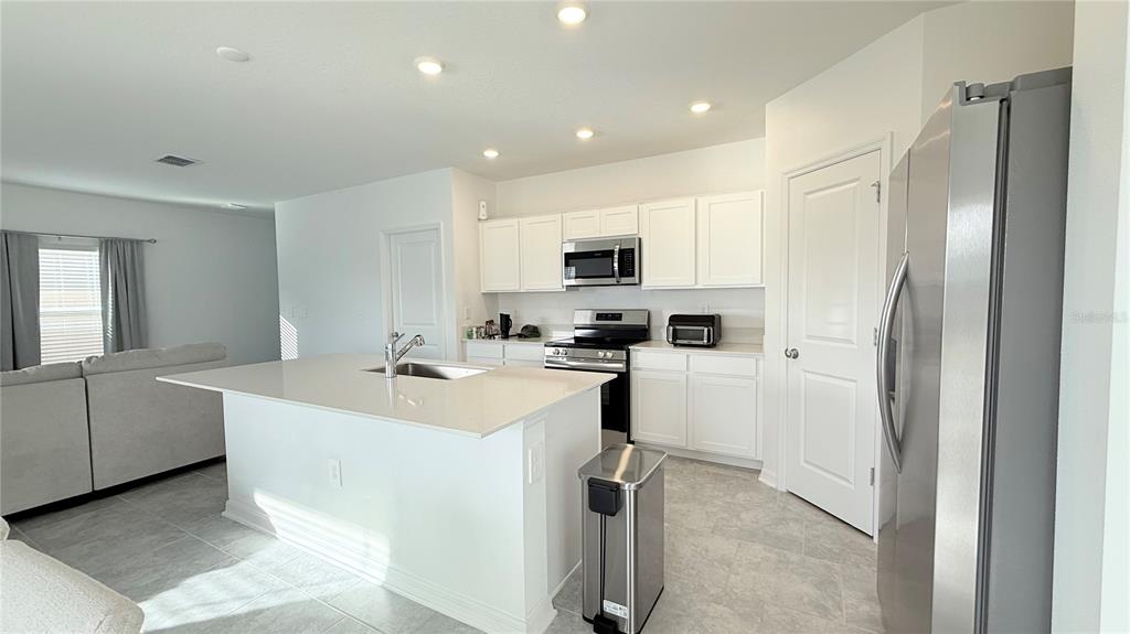1179 Tyler Loop Lake Wales, FL 33859 - Photo 7 of 25 a kitchen with white cabinets and stainless steel appliances