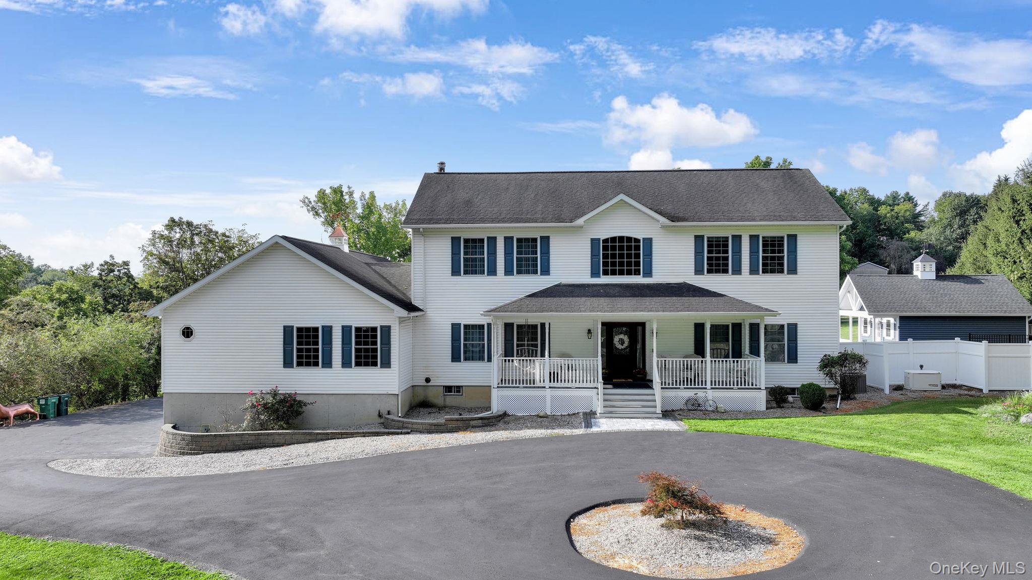 Colonial inspired home with covered porch, curved driveway, and a front yard