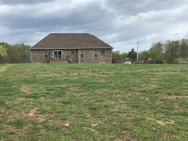 a view of a big house with a big yard and large trees