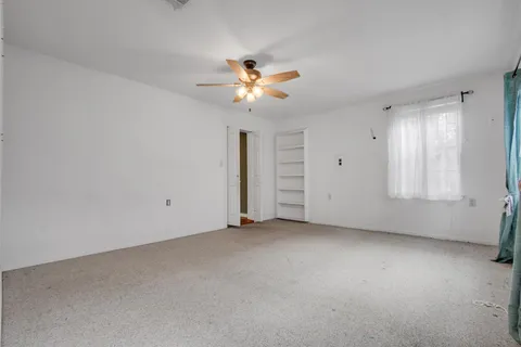 a view of a room with a ceiling fan and window