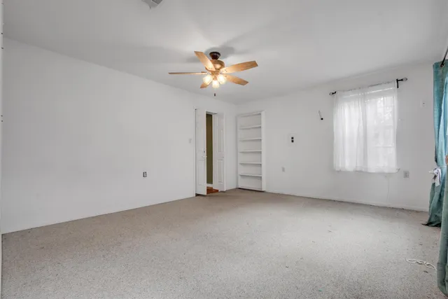 a view of a room with a ceiling fan and window