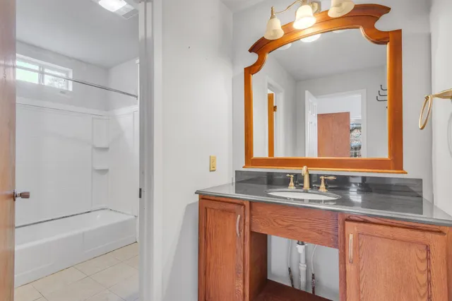 a bathroom with a granite countertop sink mirror and a bathtub