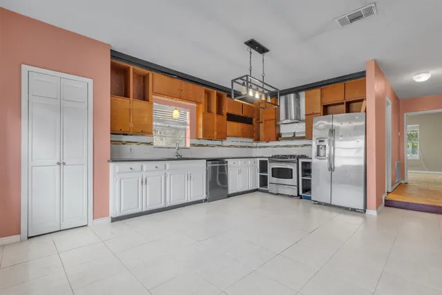 a kitchen with stainless steel appliances granite countertop a refrigerator a sink a stove and oven with wooden floor