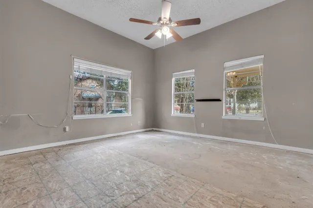 an empty room with windows and fan