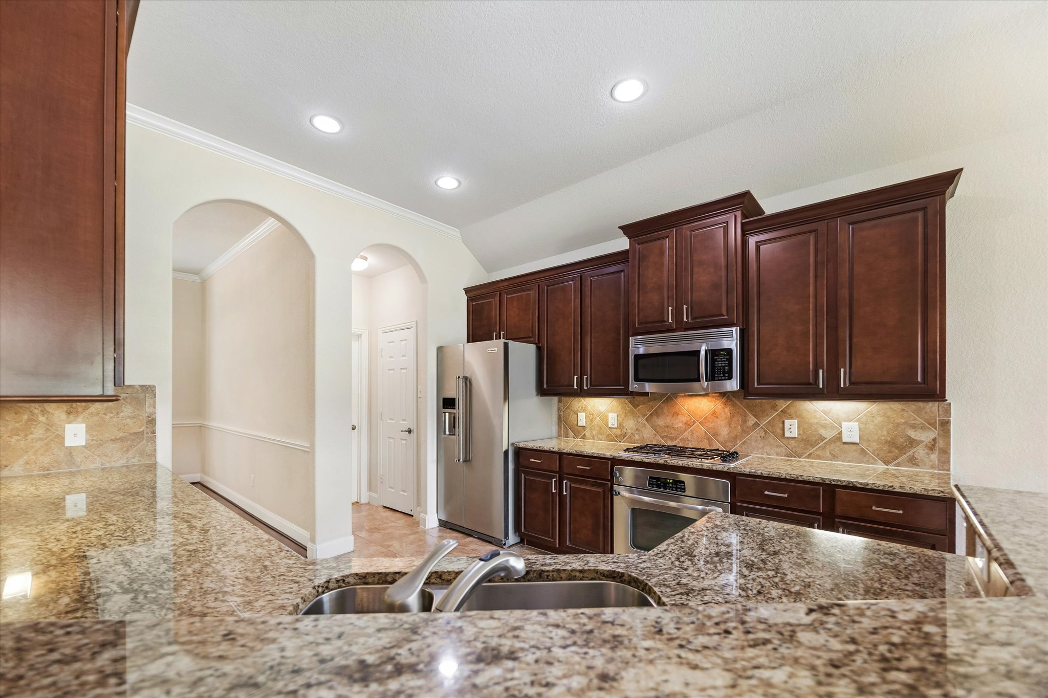 2214 Wembley Way Rosenberg, TX 77471 - Photo 21 of 35 Kitchen featuring granite countertops, dark wood-finish cabinetry, stainless steel appliances, and a tiled backsplash