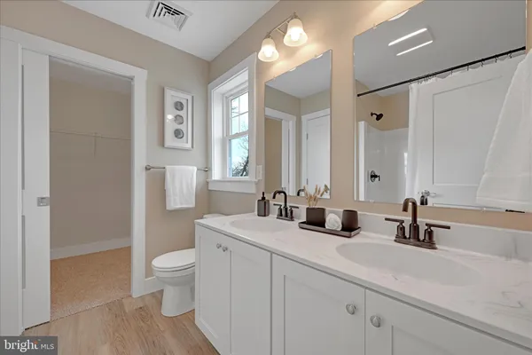 a bathroom with a double vanity sink toilet and a mirror