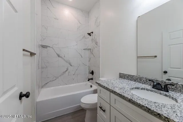 a bathroom with a granite countertop sink a toilet and bathtub