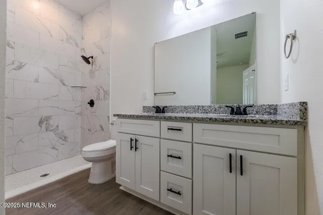 a bathroom with a granite countertop sink a toilet and shower