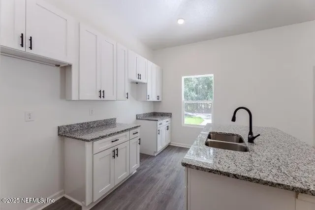a kitchen with white cabinets appliances and a window