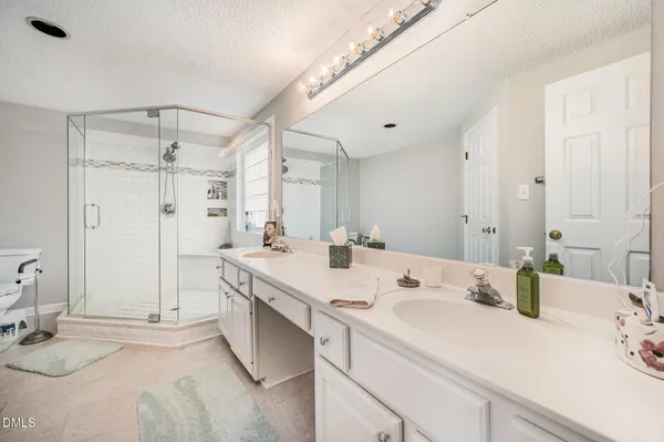 a bathroom with a sink vanity granite tub shower and a mirror
