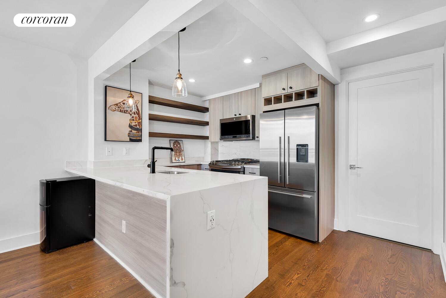 23-33 31st Road, Unit 4D Queens, NY 11106 - Photo 3 of 6 a kitchen with stainless steel appliances granite countertop a refrigerator a stove a sink and a microwave oven with wooden floor