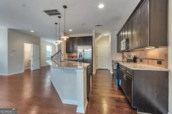 a kitchen with stainless steel appliances granite countertop a sink a stove and a wooden floors