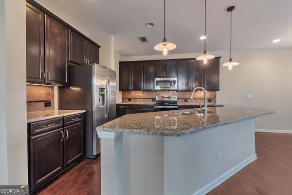 a kitchen with stainless steel appliances granite countertop a sink a stove and a refrigerator