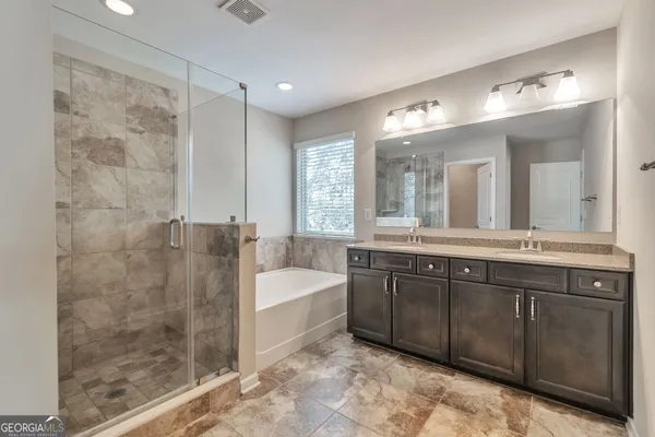 a spacious bathroom with a tub sink shower and mirror