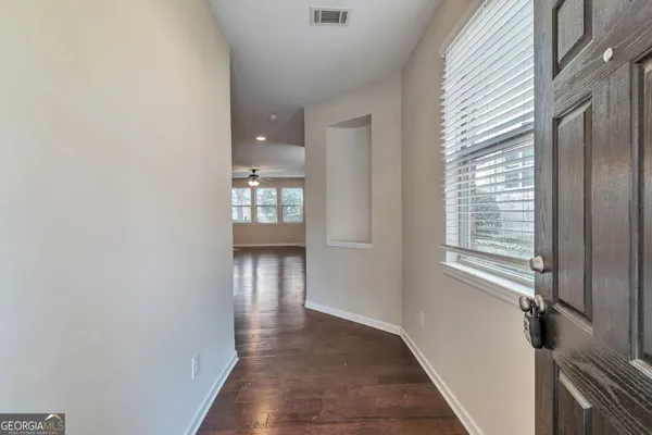 a view of an empty room with wooden floor and a window