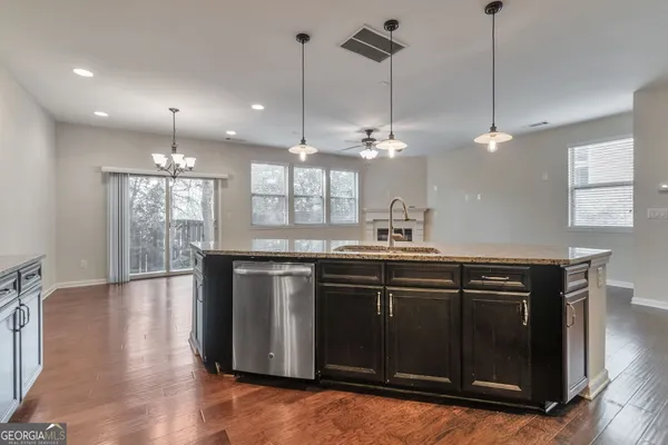 a kitchen with kitchen island granite countertop a stove a sink and a wooden floors