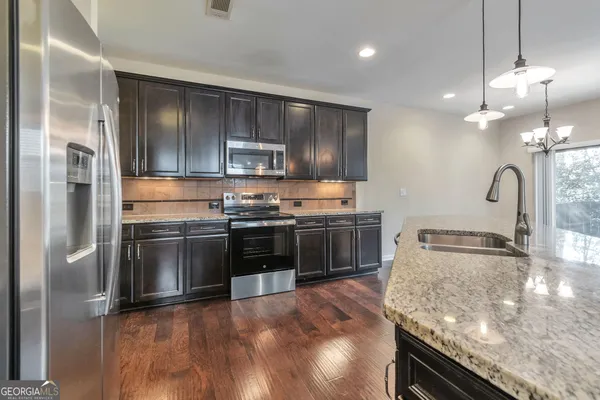 a kitchen with stainless steel appliances granite countertop a sink a stove and a refrigerator