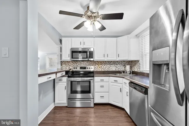 an empty room with wooden floor chandelier fan and windows