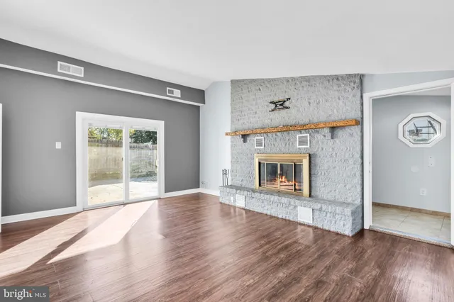 an empty room with wooden floor and a fireplace