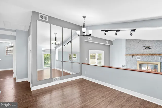 a view of a kitchen with wooden floor a ceiling fan and windows