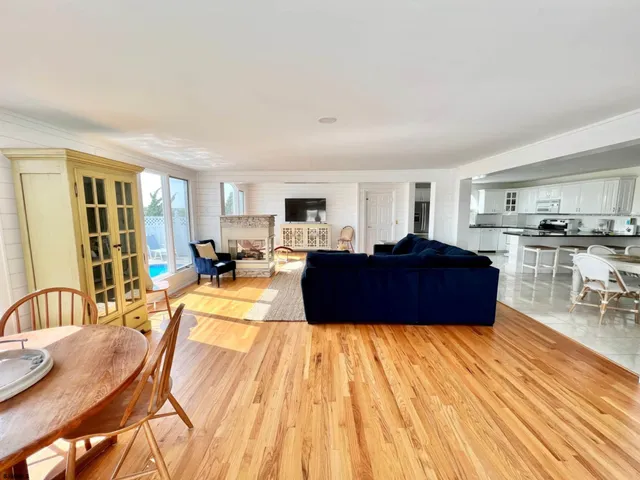 a living room with furniture a wooden floor and kitchen view