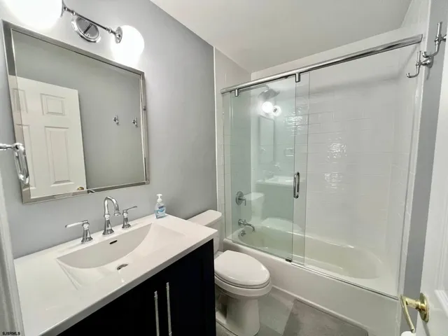a bathroom with a bathtub shower sink mirror vanity and a toilet