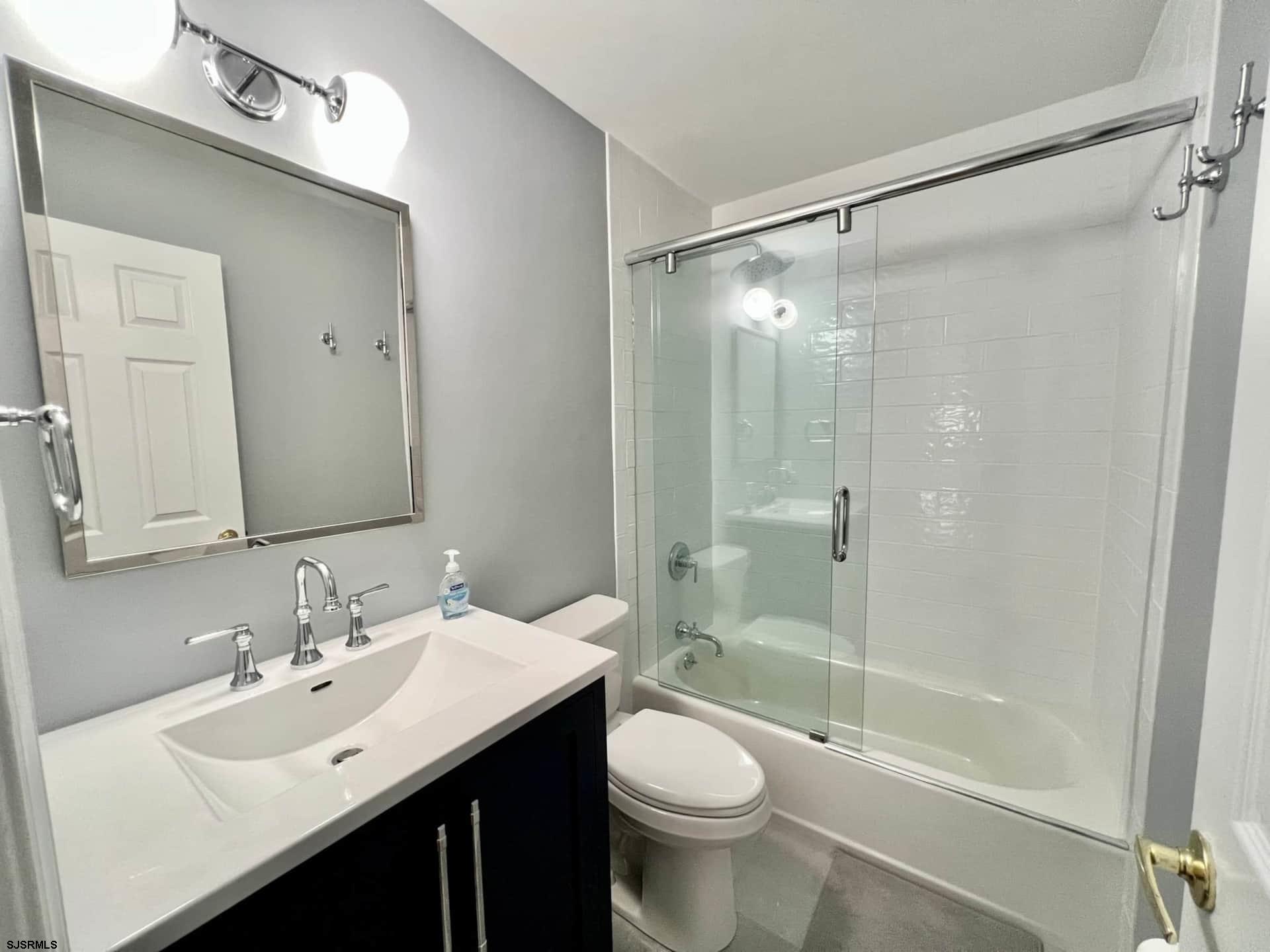24 Ocean Drive West Brigantine, NJ 08203 - Photo 32 of 48 a bathroom with a bathtub shower sink mirror vanity and a toilet