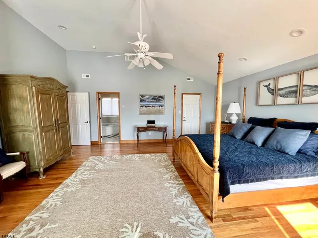 a spacious bedroom with a large bed a chandelier and dresser