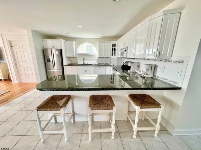 a kitchen with kitchen island granite countertop a table chairs sink and cabinets