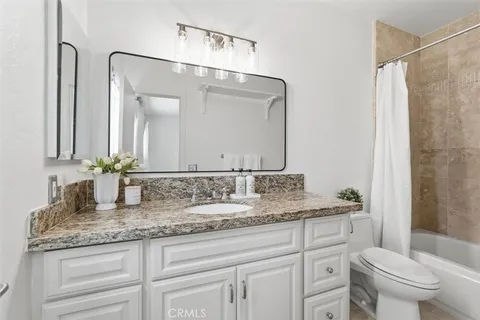 a bathroom with a granite countertop sink a toilet and a mirror