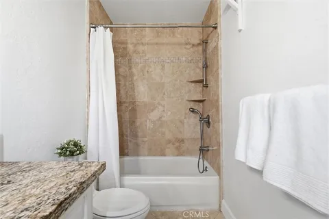 a bathroom with a granite countertop sink toilet and shower