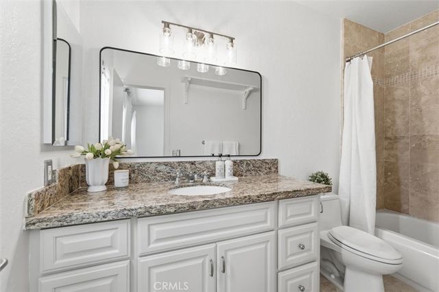 a bathroom with a granite countertop sink a toilet and a mirror