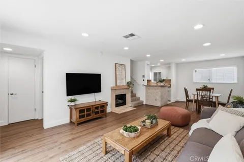 a living room with furniture a flat screen tv and kitchen view