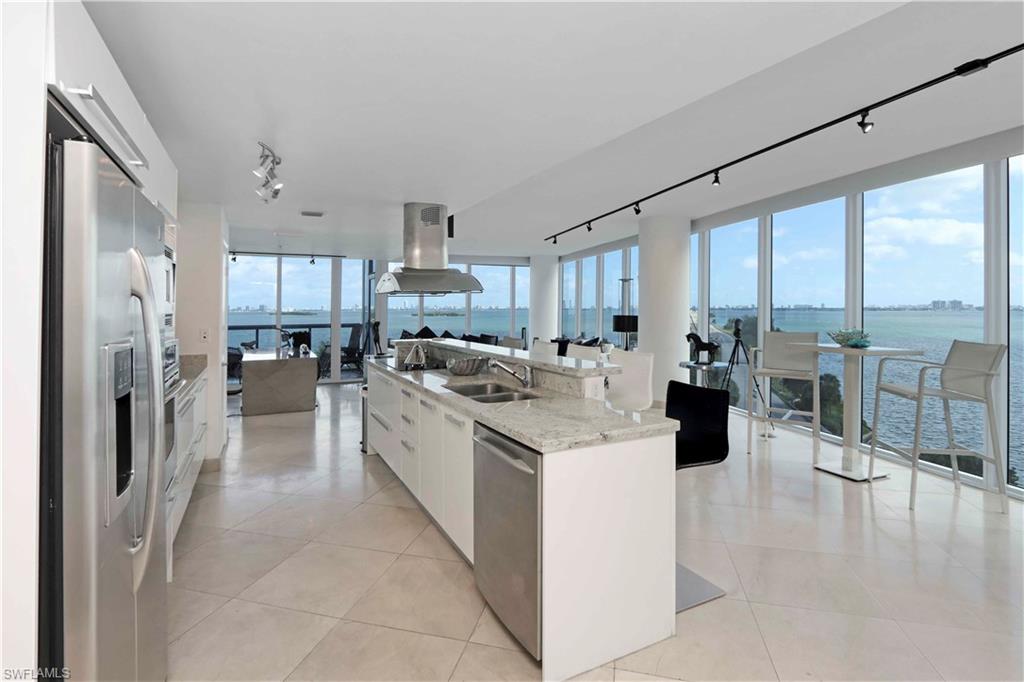 601 Northeast 36th Street, Unit 712 Miami, FL 33137 - Photo 15 of 28 a kitchen with stainless steel appliances kitchen island granite countertop a refrigerator oven a sink dishwasher and white cabinets next to a window