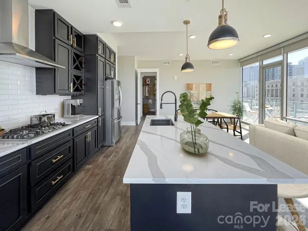 a kitchen with stainless steel appliances sink stove refrigerator and wooden floor