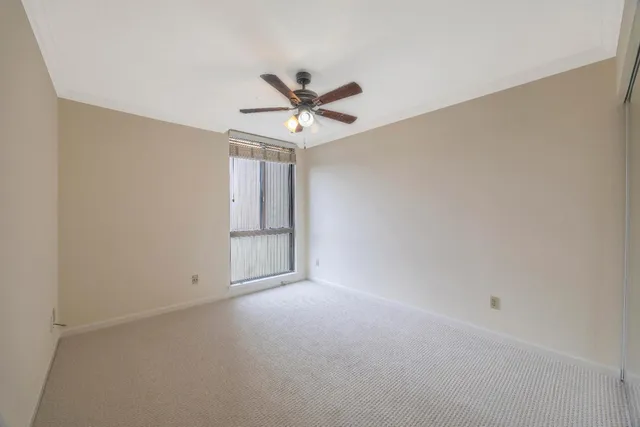 an empty room with windows and fan