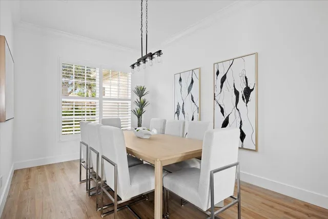 a kitchen with stainless steel appliances a refrigerator a stove a sink a dining table and chairs with wooden floor