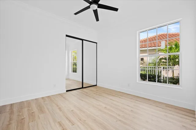a view of an empty room with a window and wooden floor