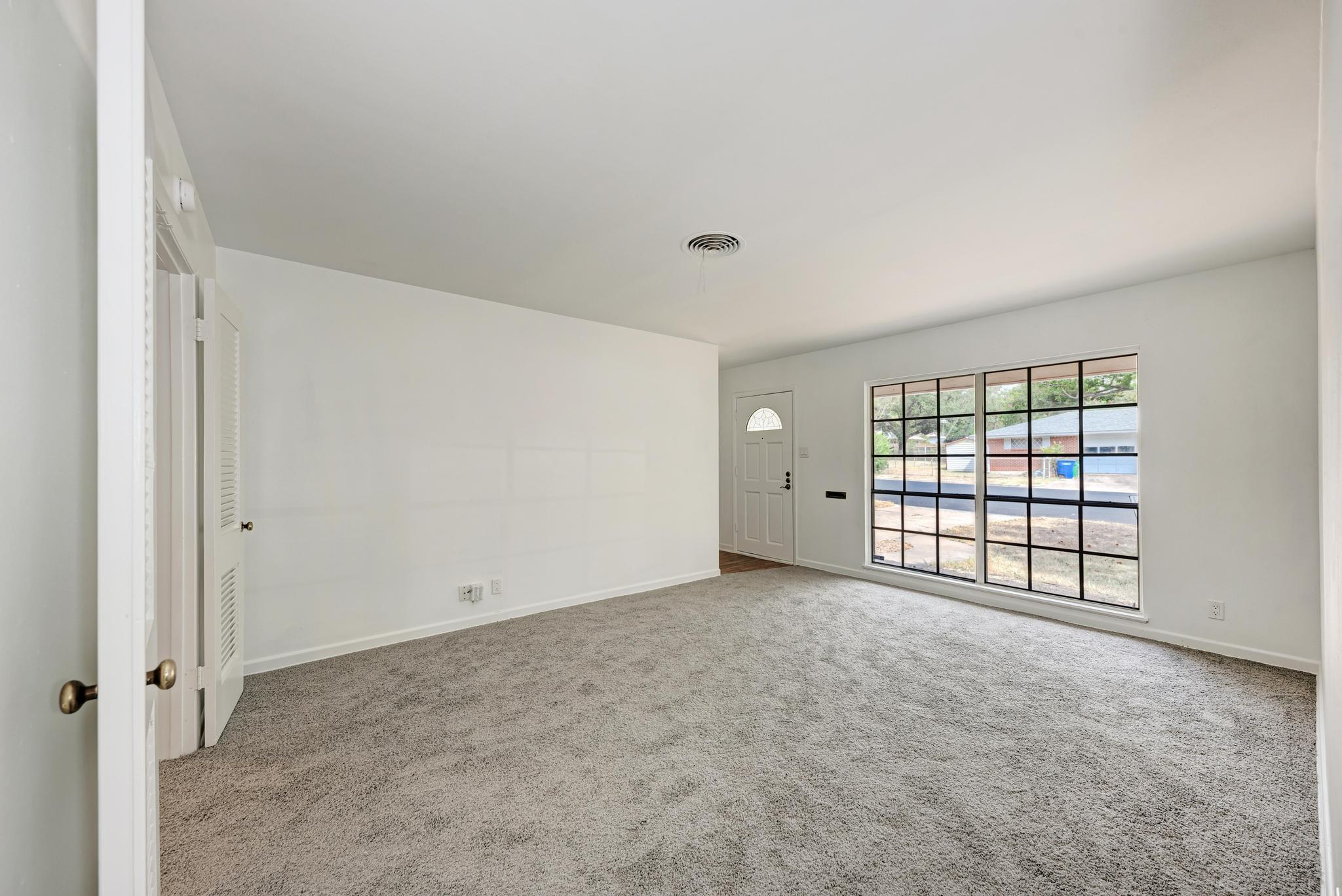 7804 Rutgers Avenue Austin, TX 78757 - Photo 31 of 32 A spacious living room features wall-to-wall carpeting and a large multi-pane window.