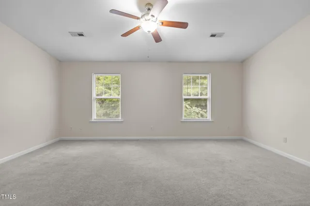 an empty room with windows and fan