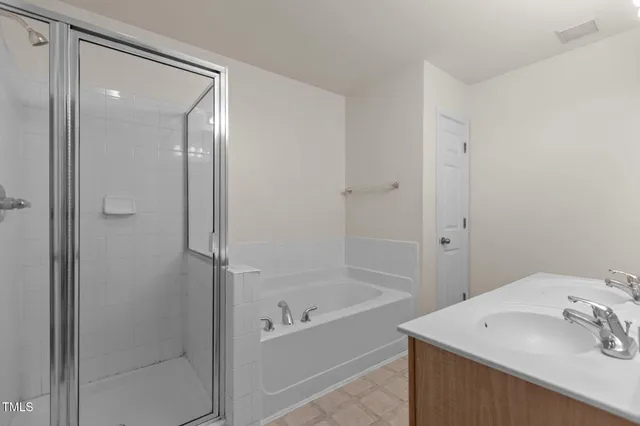a bathroom with a tub sink vanity and shower