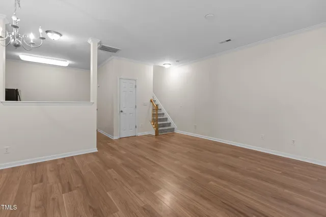 a view of an empty room with wooden floor and a staircase