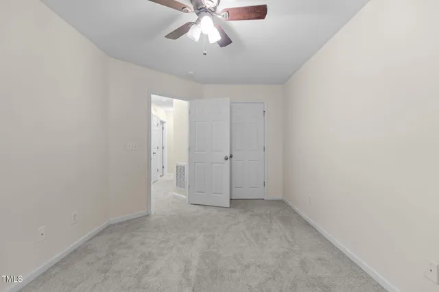 an empty room with chandelier fan and windows