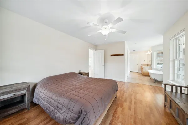 a view of an empty room with wooden floor and a ceiling fan