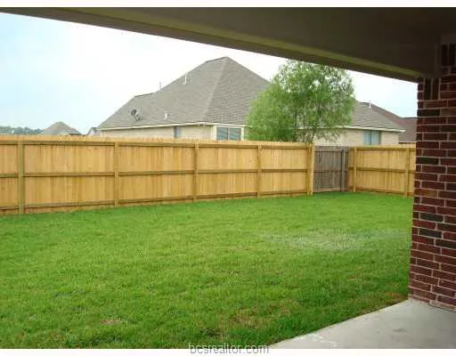 a view of yard with small cabin and wooden fence
