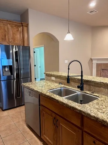 a kitchen with granite countertop a sink and refrigerator